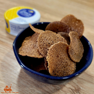 Un bol bleu contenant des chips de sarrasin rondes et en arrière plan une boîte de tartinade de maquereaux de la marque La compagnie bretonne.