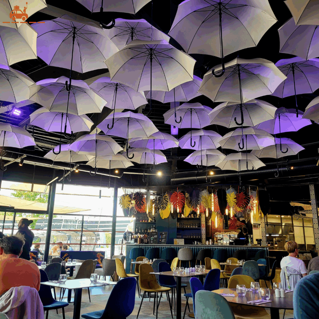La salle du restaurant l'atelier des saveurs du Futuroscope : décoration originale (parapluies) et tables et chaises cosy