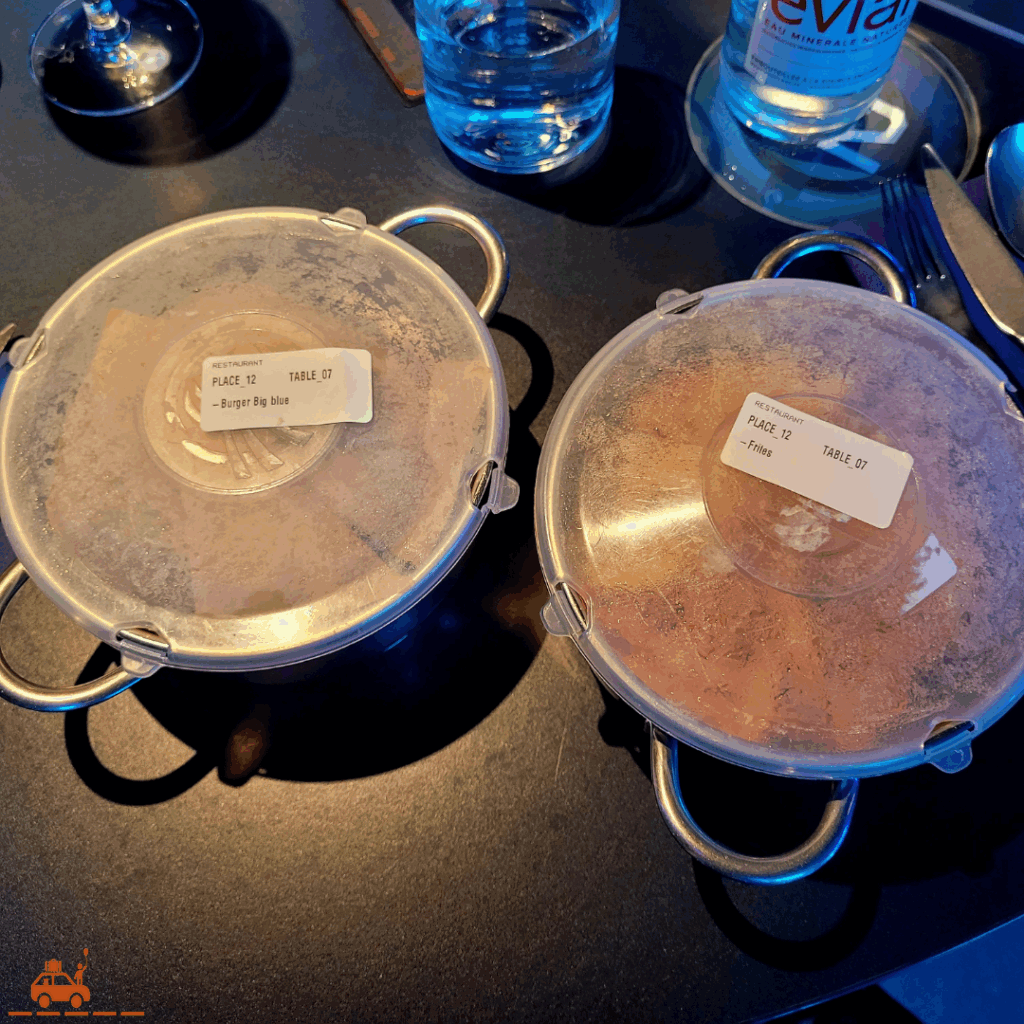 Deux cassolettes en inox avec un couvercle en plastique. Une étiquette avec le N° de la table et de la place se trouve sur le couvercle.