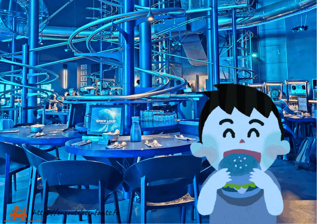 La salle du Rollercoaster Restaurant Space Loop au Futuroscope avec ses rails, ses tables, chaises et écrans tactiles et sa couleur bleuté et un petit garçon qui mange un hamburger bleu, le Big Blue Burger