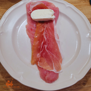 Pour préparer un cordon bleu maison à l'italienne, ma recette est d'étaler l'escalope de dinde sur une assiette et de la recouvrir d'une tranche de jambon de parme et d'une tranche de mozzarella di bufala.