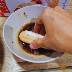 Etape 3 de la recette du tiramisu italien au mascarpone - Trempez les biscuits à la cuillère dans le café afin de les imbiber légèrement