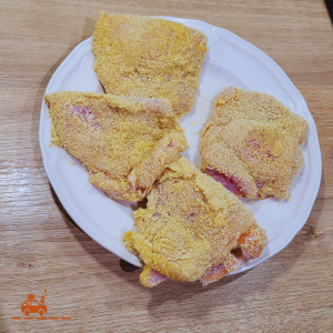 4 cordons bleus maison préparés et panés et posés sur une assiette blanche avant la cuisson