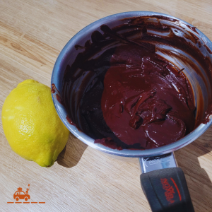 Casserole contenant une préparation pour faire des truffes au chocolat maison (mélange de beurre, de chocolat et d'un jaune d'oeuf) avec 1 citron posé à côté