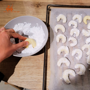 Dernière étape de la recette des Vanille Kipferl : tremper les biscuits dans un bol de sucre glace, de façon à les recouvrir entièrement de sucre glace.