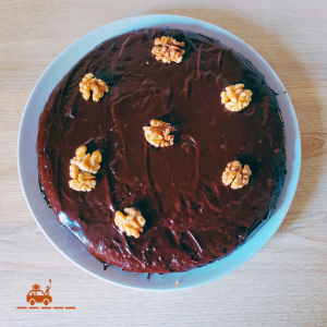 Gâteau aux noix du Périgord avec un glaçage chocolat et décoré de cerneaux de noix posé sur une assiette grise