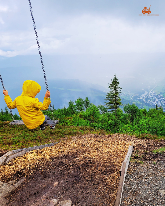 Enfant sur une balançoire au sommet du Mont Hanguren en Norvège sous la pluie