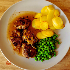 Kjøttkaker (boulettes de bœuf norvégiennes) servies avec une sauce brune, des pommes de terre sautées et des petits pois