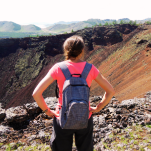 Clémentine de dos avec un sac à dos, contemplant un cratère en Mongolie