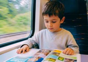 Petit garçon qui s'occupe dans le train en lisant un magazine